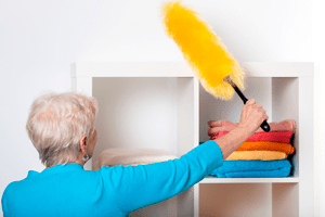 Older woman practicing dust control in her home. 