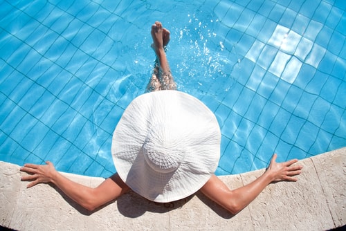 woman laying in the pool with a hat on